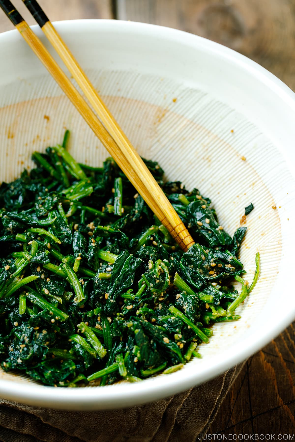 A Japanese suribachi mortar containing blanched spinach salad seasoned with sesame seeds, soy sauce, and sugar.